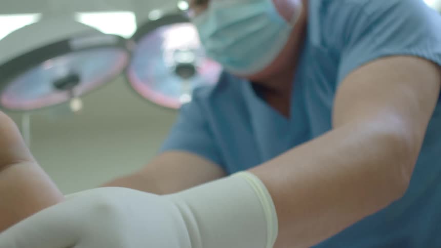 From the patient's point of view, a surgeon in scrubs examines the sole of their foot in a sterile hospital operating room