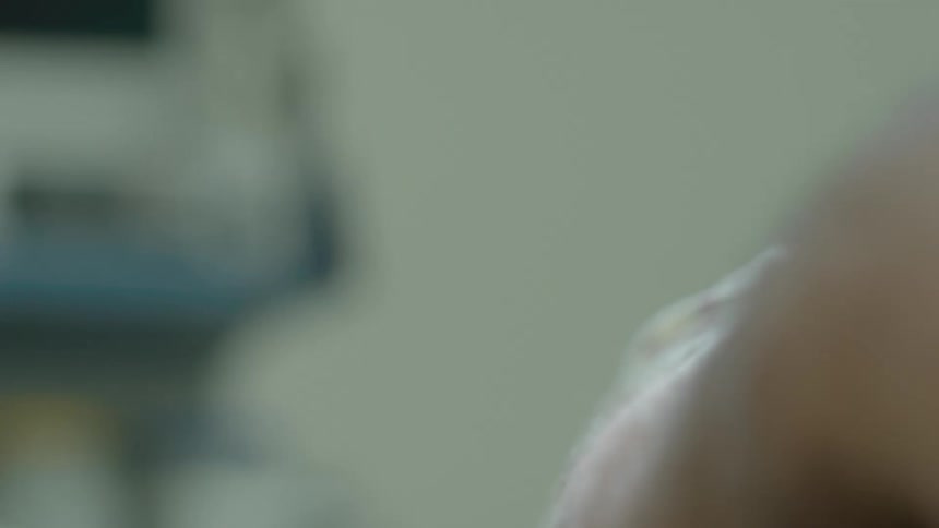 A slow focus pull reveals a hospital vital signs monitor displaying a patient's heart rate and oxygen levels