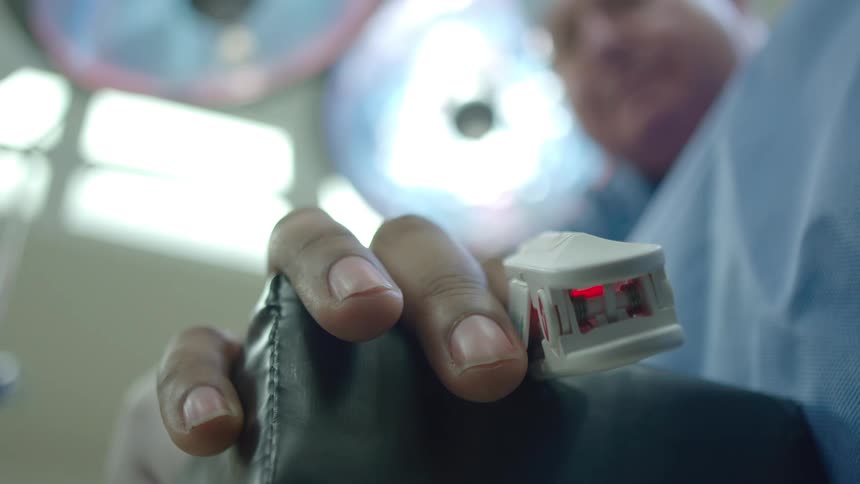 A patient's point of view of a pulse oximeter on their finger in a hospital operating room while a doctor checks on them