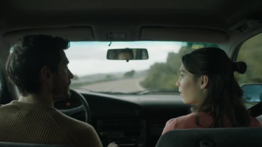 A man and woman ride in a car