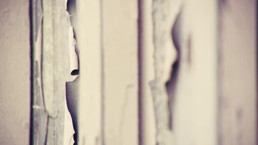 An abstract macro shot reveals the texture of old, cracked, and peeling paint on a decaying wall