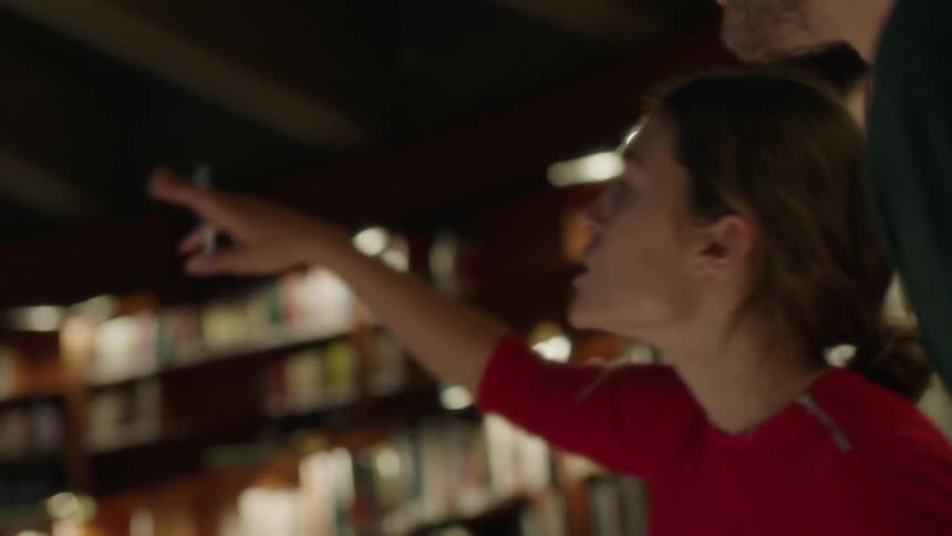 A man and woman pointing and talking about something inside a building