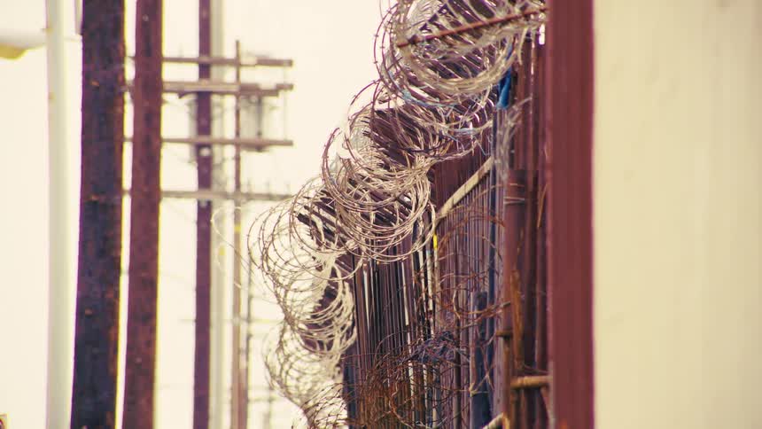 Close up of coiled barbed razor wire on a security fence in an industrial area