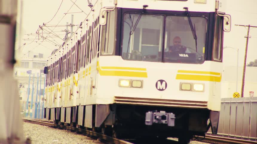 The Los Angeles metro train to Long Beach slowly approaches the camera and passes by on an overcast day