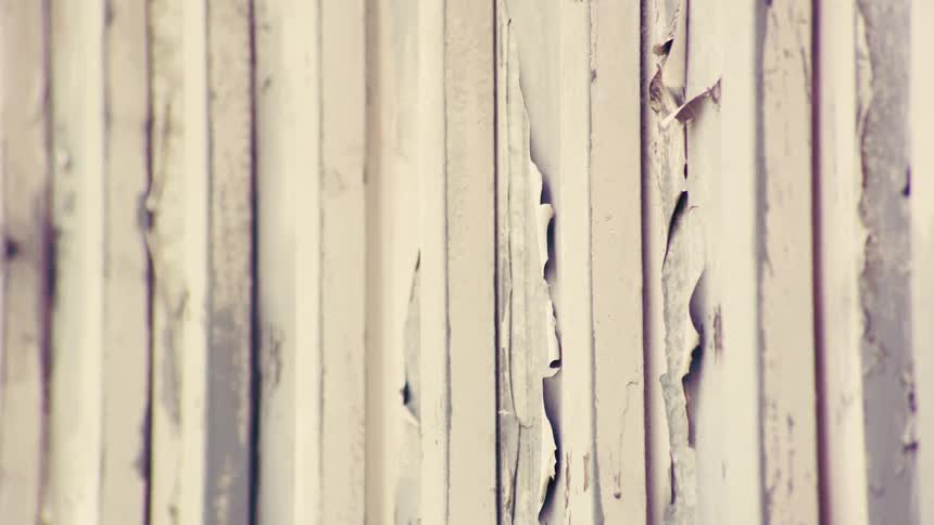 A static close-up shot of a rustic, weathered white wooden wall with peeling paint