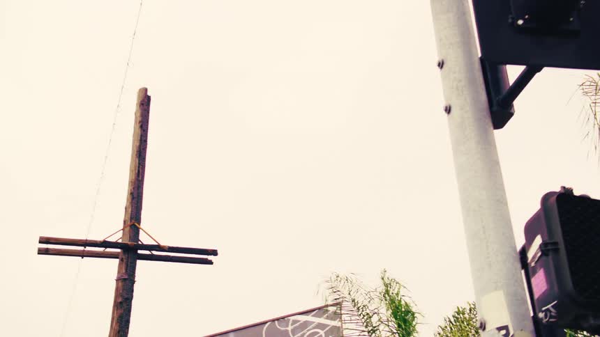 Low-angle pan revealing a Central Avenue street sign, a traffic light, and a school crossing sign in an urban setting