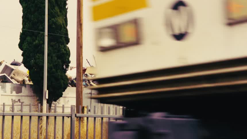 A passing train reveals a large pile of garbage and discarded items in an urban junkyard