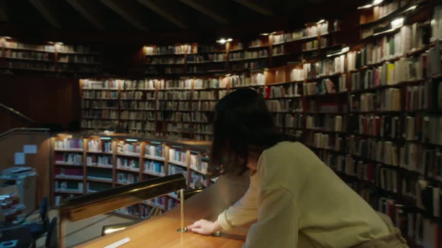 A woman walks around a library turning off lights