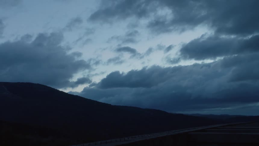 Clouds move across hills at dusk