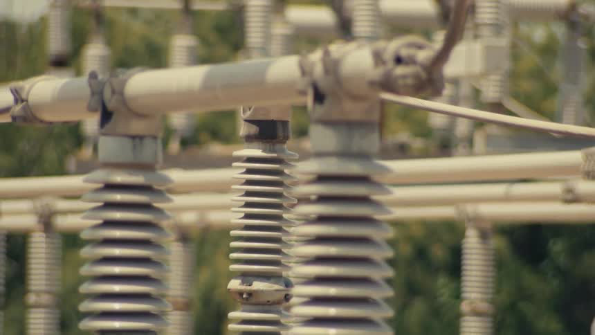 Slow tilt down shot reveals the insulators and infrastructure of a high-voltage electrical substation