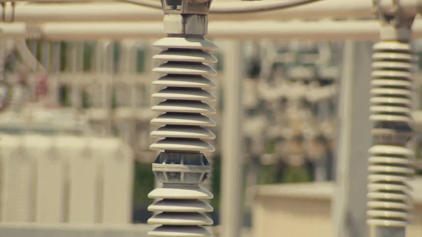 A slow tilt down shot revealing the complex network of wires and ceramic insulators at an electrical power substation
