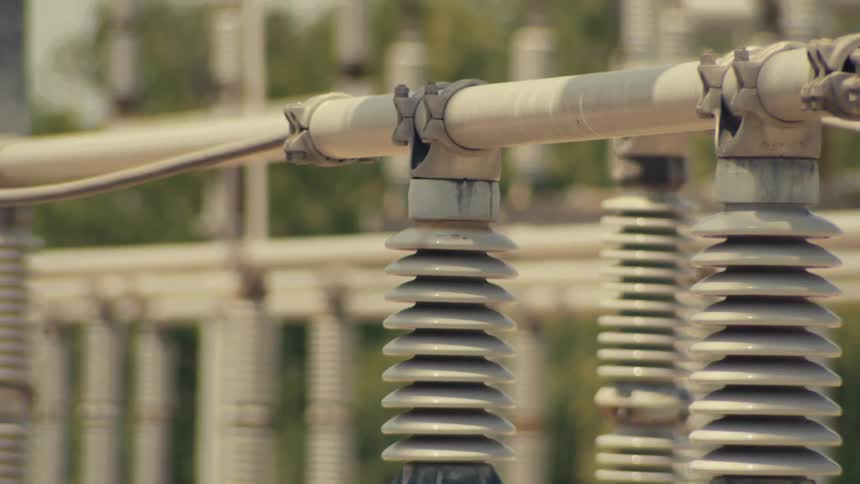 A detailed slow-motion tilt-up revealing the intricate ceramic insulators and connections at a high-voltage power substation
