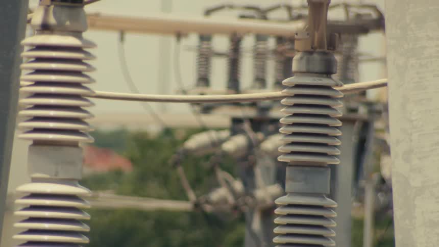 A slow rack focus across the insulators and wires of an electrical power grid substation