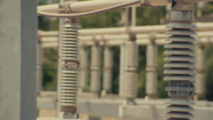 A slow-panning close-up shot reveals the intricate network of ceramic insulators at a high-voltage electrical substation
