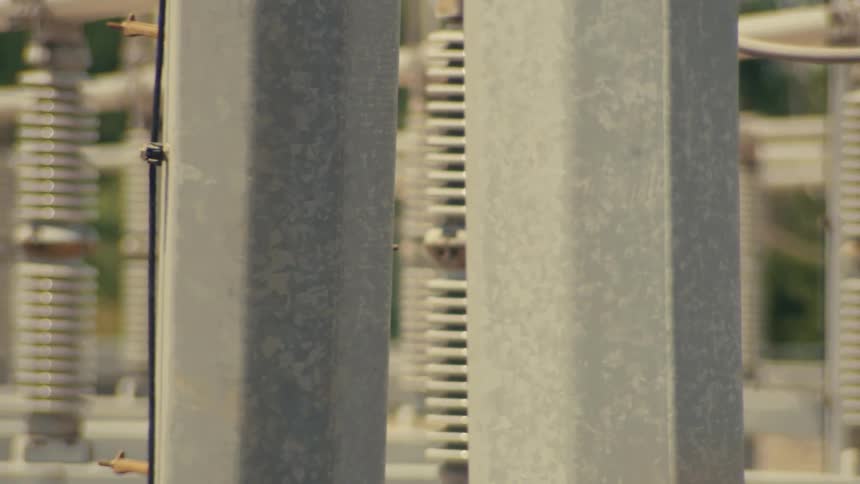 A slow, detailed pan across high-voltage ceramic insulators at an electrical power substation