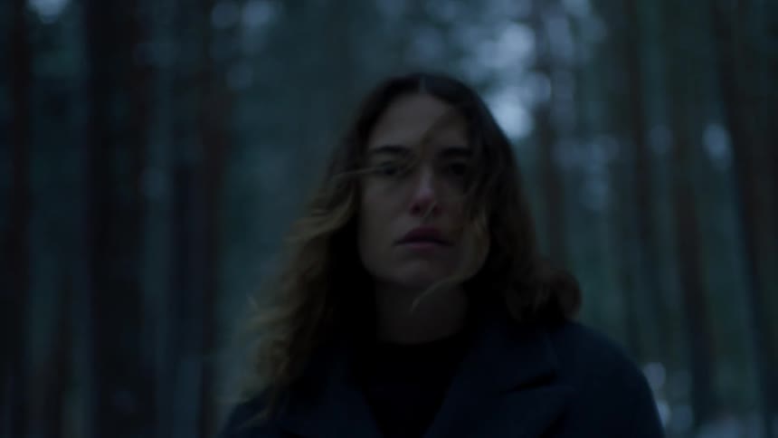 A woman walks in the windy forest