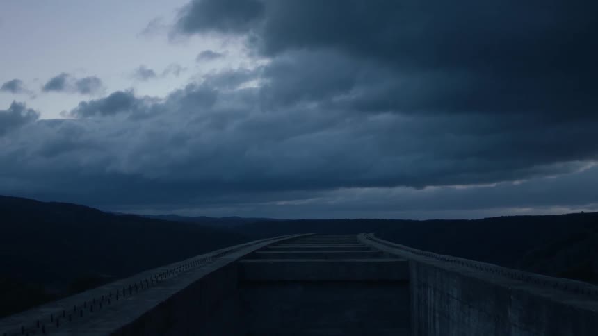 Clouds float over mountains and concrete at dusk