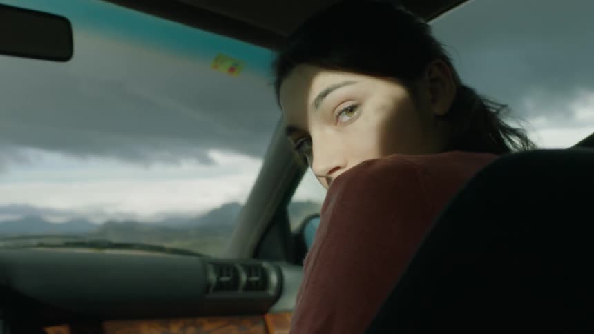 A woman in the passenger seat looks over her shoulder to the back