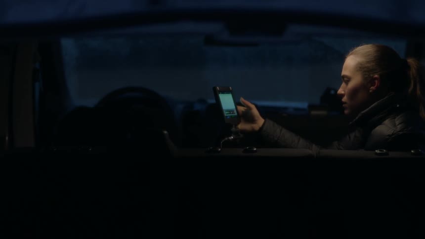 Woman using a smartphone while sitting in a car at night
