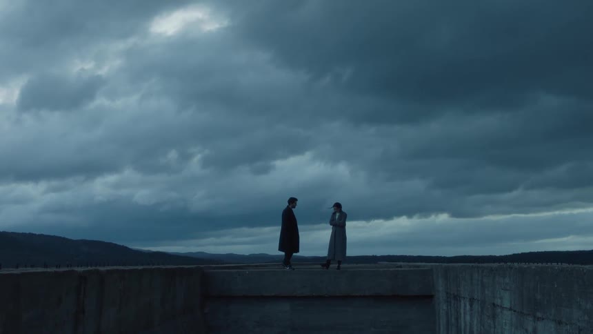 Two people walk on a stone wall ahead