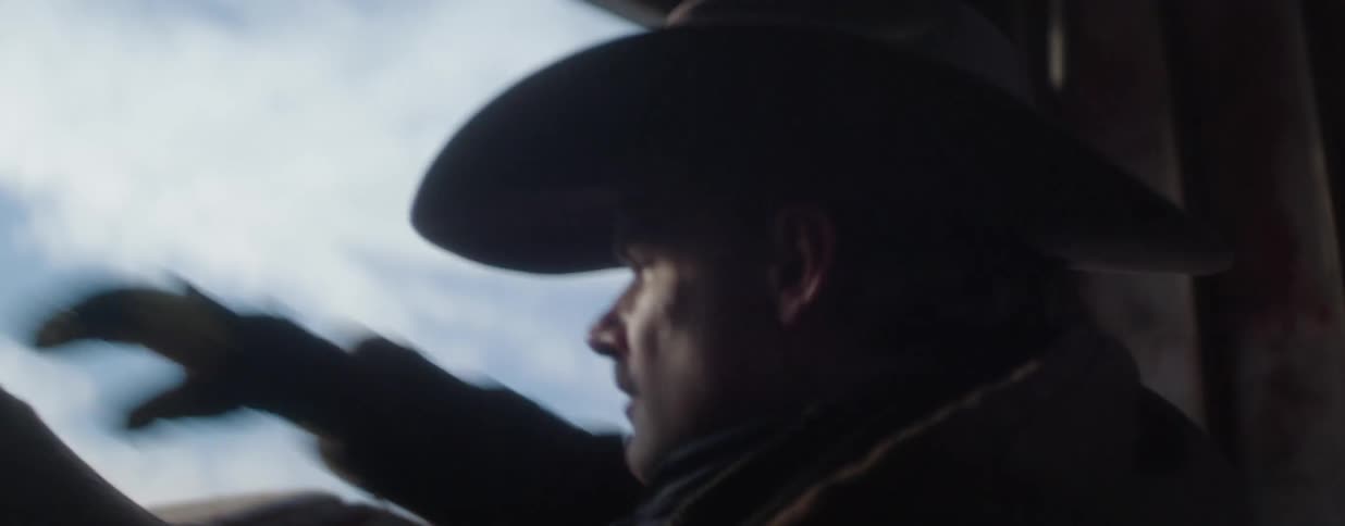 Cinematic slow-motion close-up of a thoughtful cowboy looking out the window of a moving vehicle