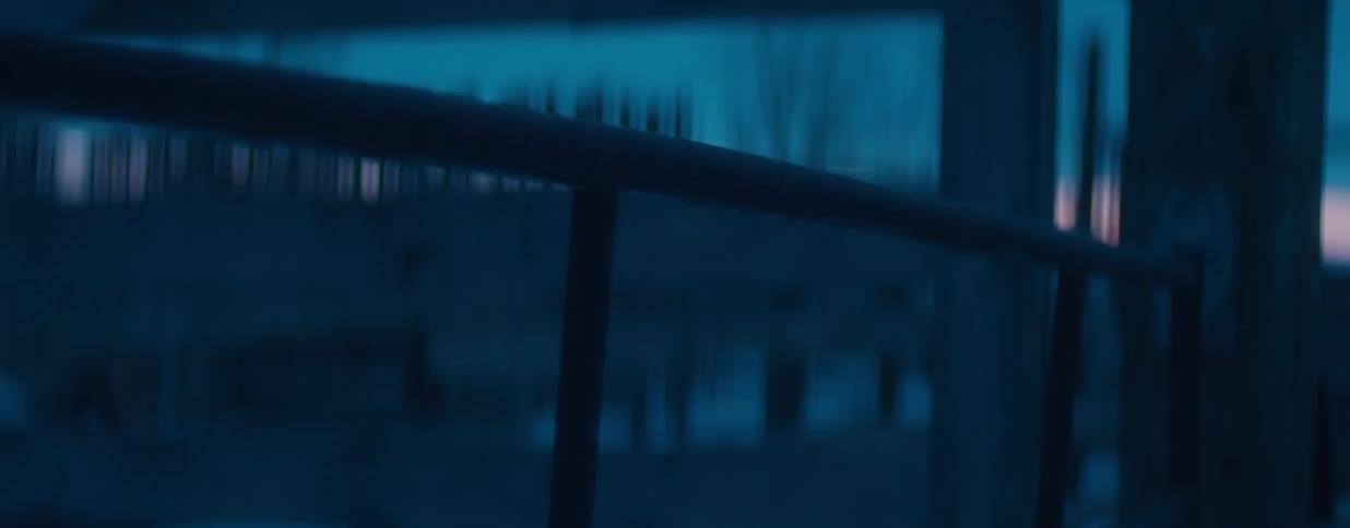 A mysterious, moody abstract shot of a dark railing against a blurry, dark blue background at night