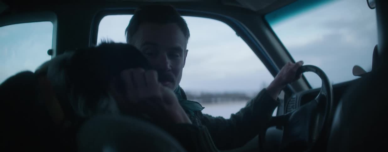 A man with a mustache drives his car with his faithful dog, affectionately petting its head as they travel together