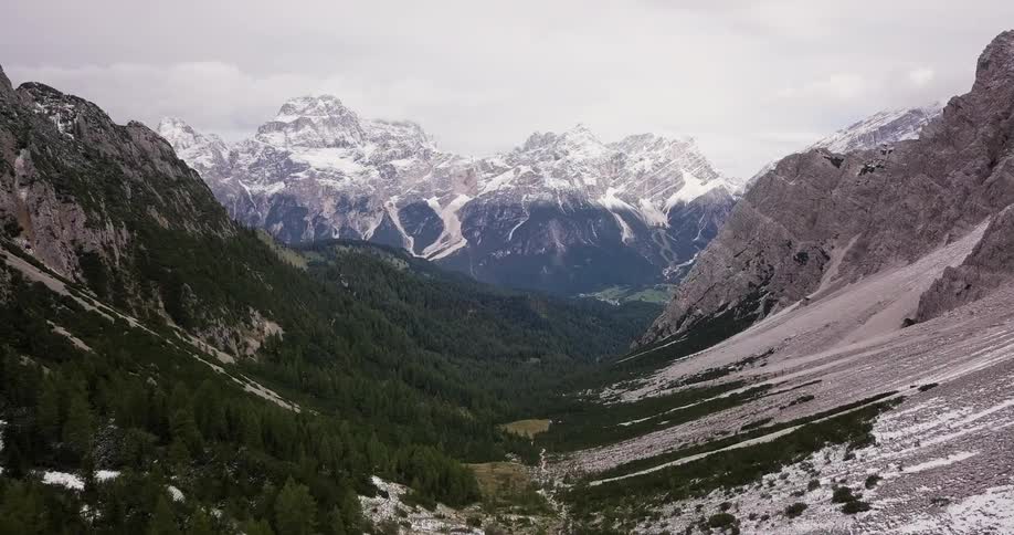 Mountain range partially covered in snow and trees on cloudy day