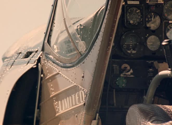 A slow pan from the vintage cockpit to the exterior and propeller of a seaplane resting on the water