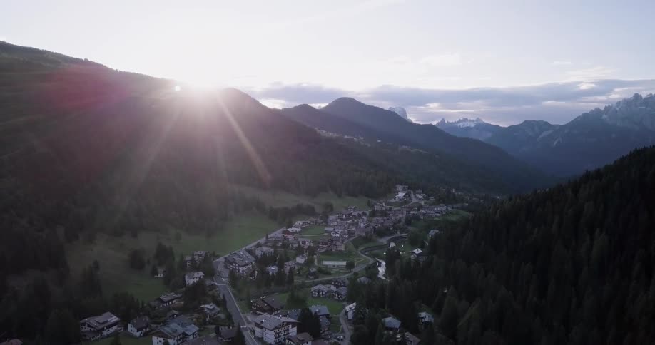 The sun is setting behind the mountain near a town