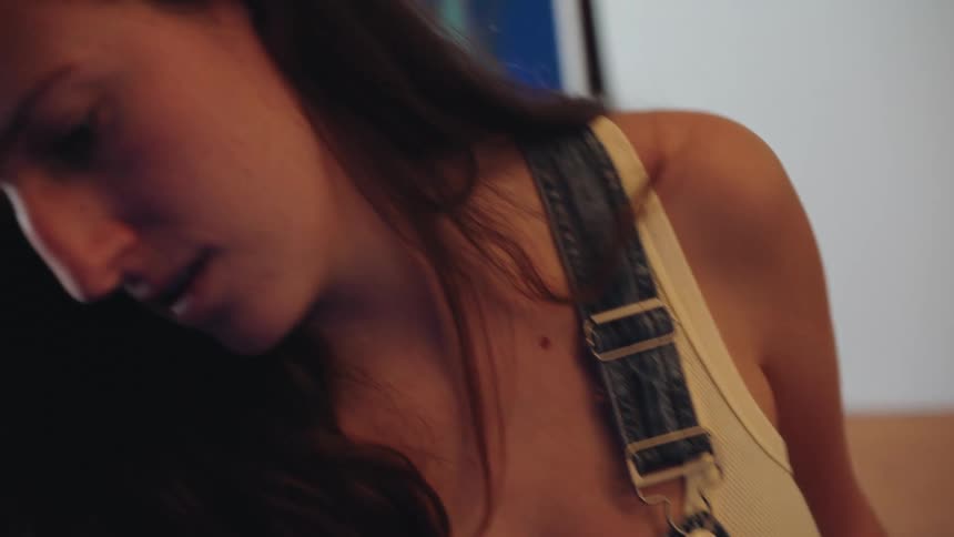Slow motion close-up reveals a female artist in paint-stained overalls, intensely focused on her work