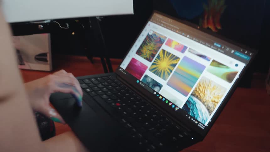 An artist in her studio uses a laptop to browse for creative inspiration while sitting in front of her work-in-progress abstract canvas