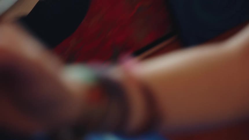 A focused female artist concentrates as the camera transitions from her face to a close-up of her hand painting on a canvas