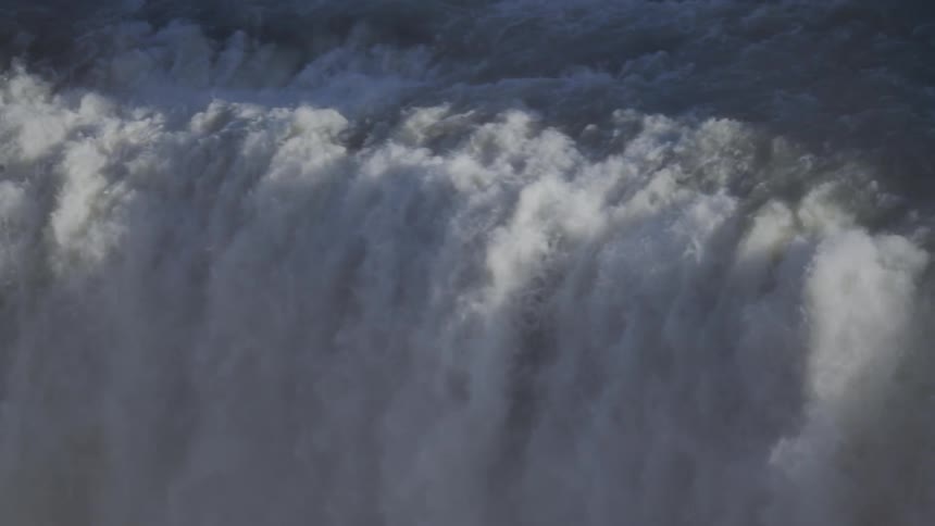A powerful wall of water thunders over the edge of a massive waterfall