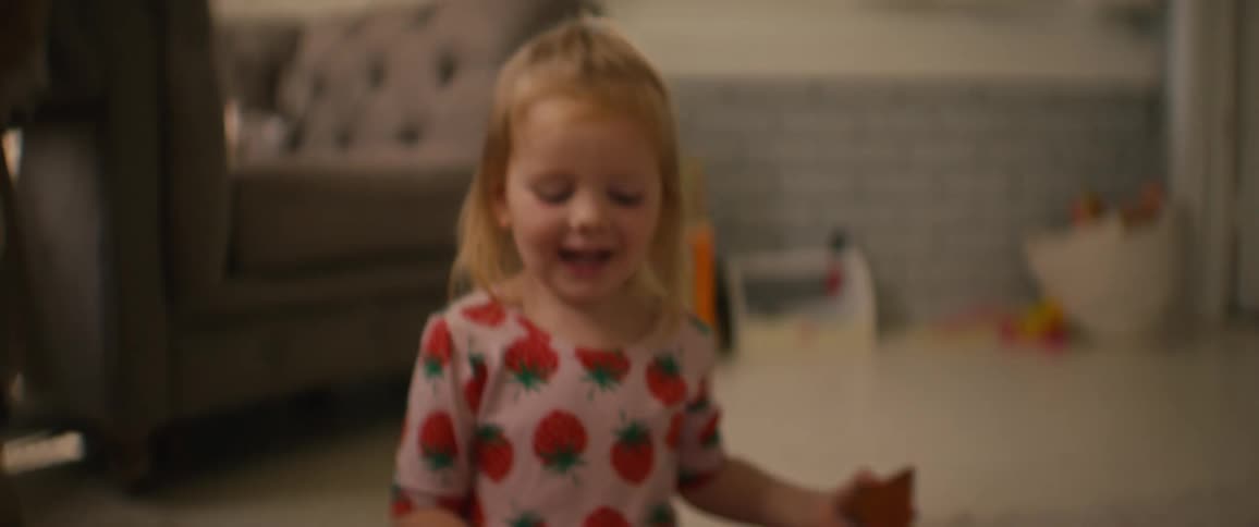 A happy toddler girl knocks down a colorful magnetic tile tower she built