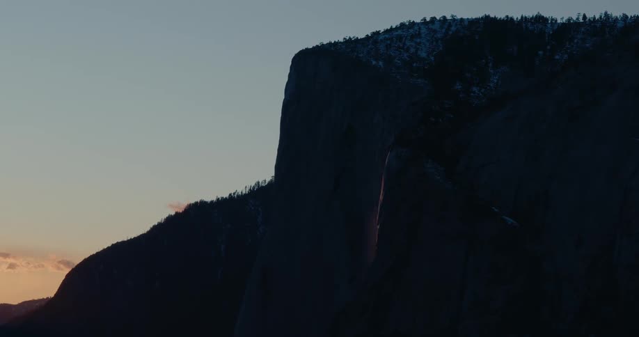 A static shot of a majestic mountain silhouetted against a clear twilight sky as the last light fades