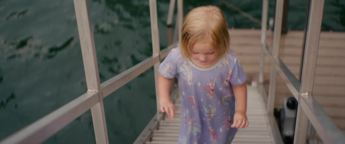 High angle shot of a young girl in pajamas walking up a ramp from a dock
