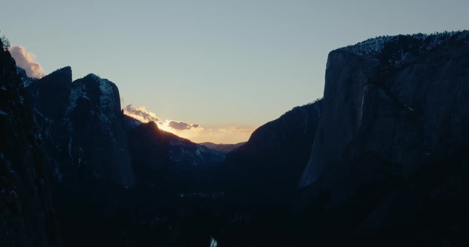 The last light of sunset glows behind the silhouetted mountains of Yosemite Valley from a majestic overlook