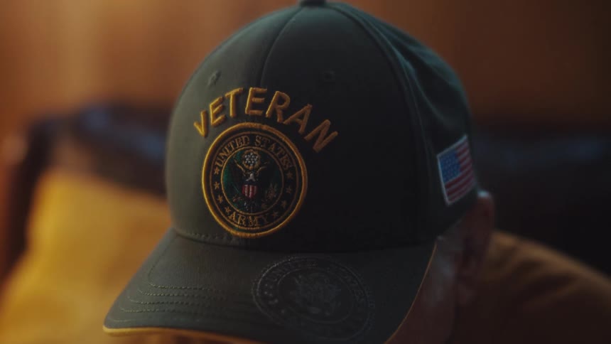 Close-up of an elderly man's U.S. Army Veteran hat as he sits indoors in a quiet, reflective moment