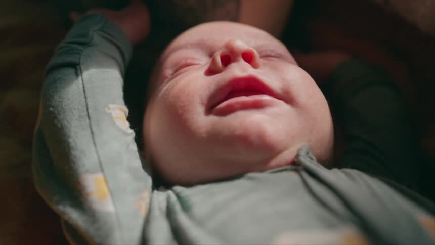 Close up of a newborn baby sleeping peacefully and smiling in the warm sunlight