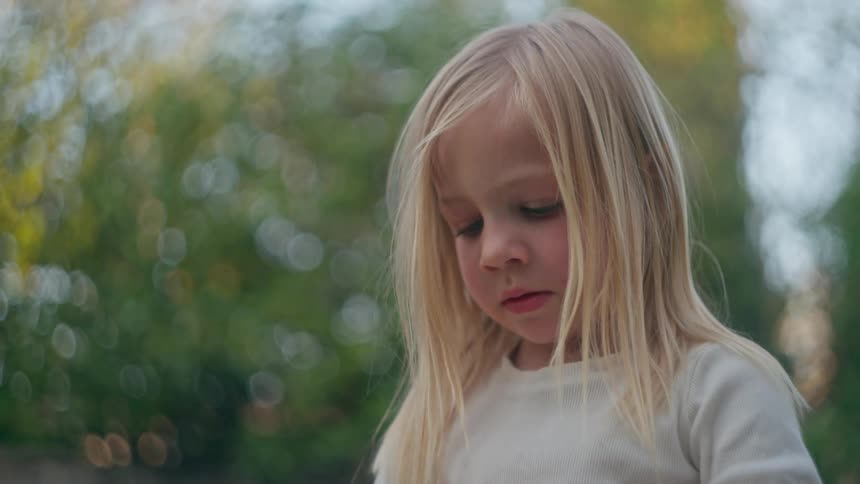 A beautiful young blonde girl looks up with wonder and points at something amazing