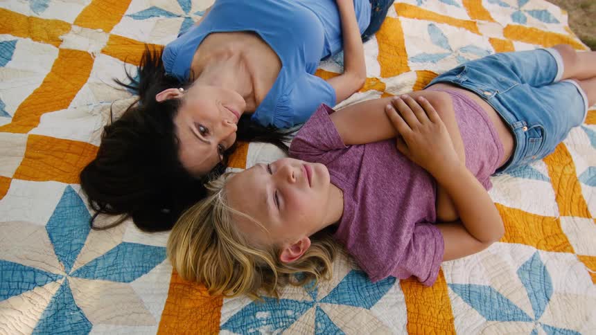 Overhead shot of a loving mother and son relaxing and sharing a quiet moment together on a colorful quilt