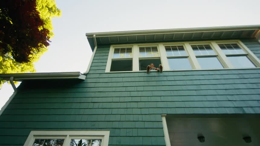 Children play catch in the backyard tossing a ball from an upstairs window on a sunny day