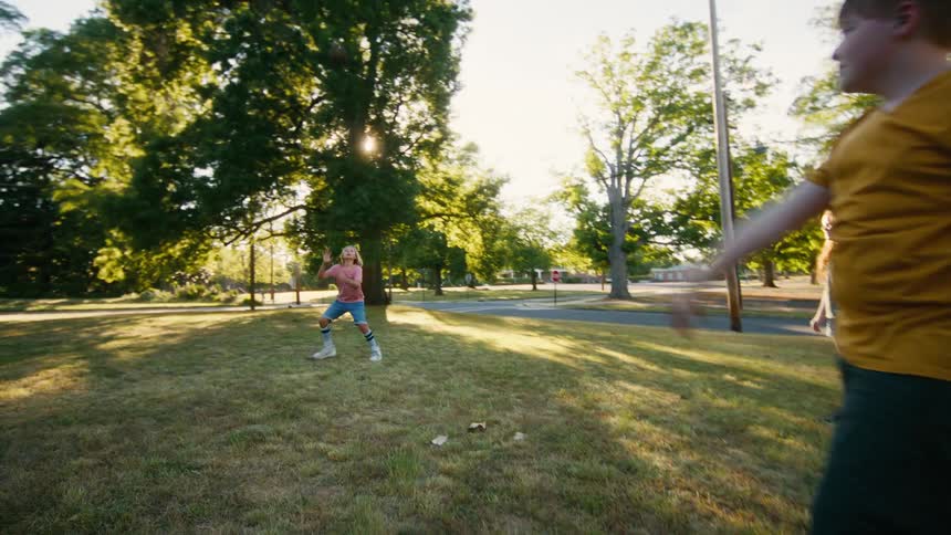 A group of three children enjoy a sunny summer day playing catch with a baseball in the park
