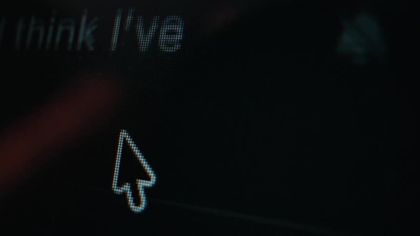 A macro shot captures a cursor scrolling quickly through digital text on a dark computer monitor