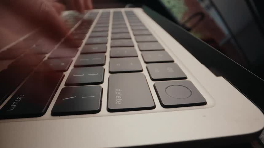 A frenetic time-lapse shows a close-up of a woman's hands typing quickly on a laptop keyboard and repeatedly pressing the delete key