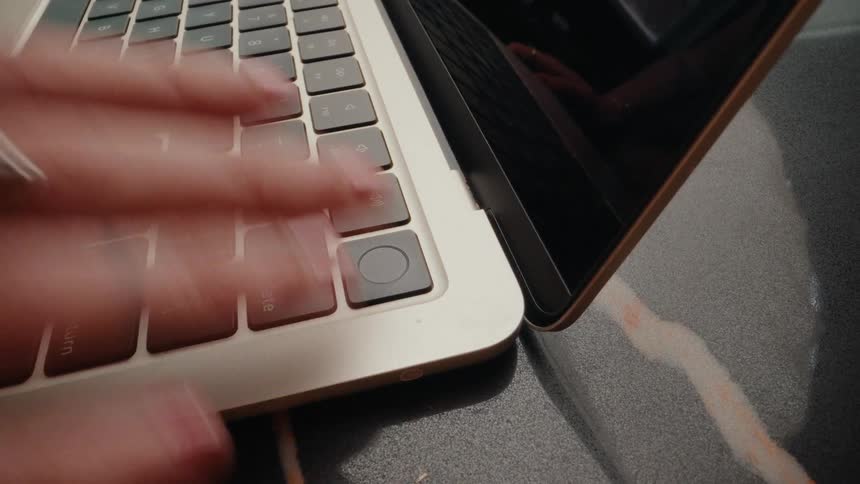 A person logs into their laptop with a fingerprint scan and begins typing on the keyboard