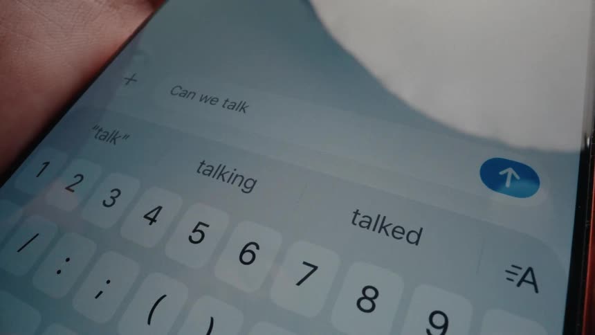 Close-up of a person typing and sending the text message 'Can we talk?' on their smartphone
