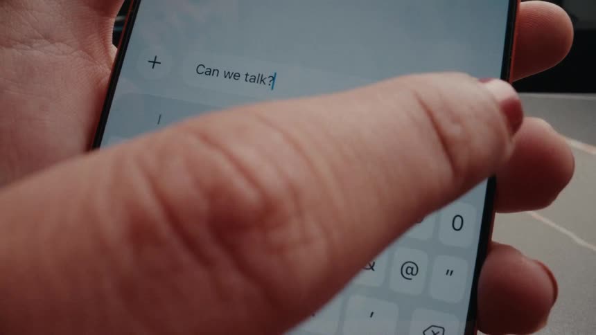 A close-up shot of a person sending an important text message asking 'Can we talk?' on their smartphone