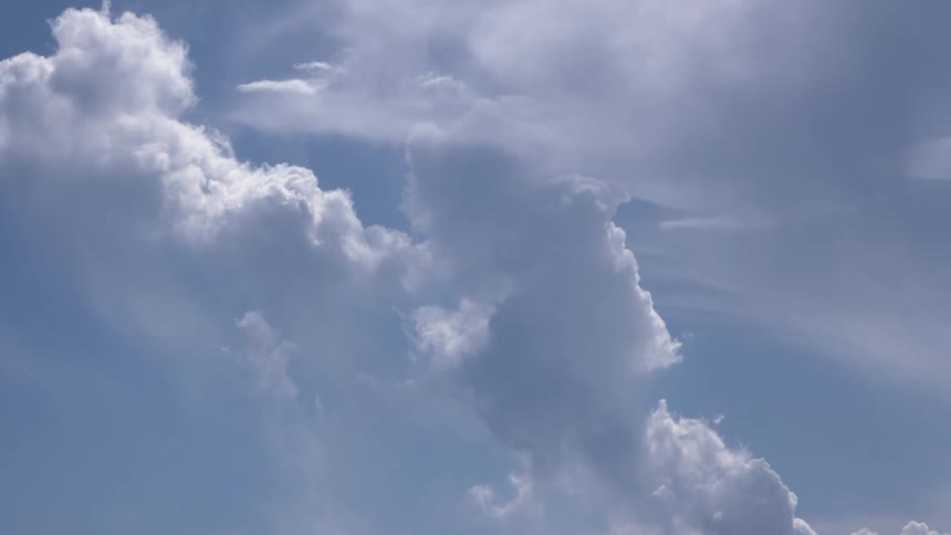 Time-lapse of white cumulus clouds building and dissipating against a bright blue sky